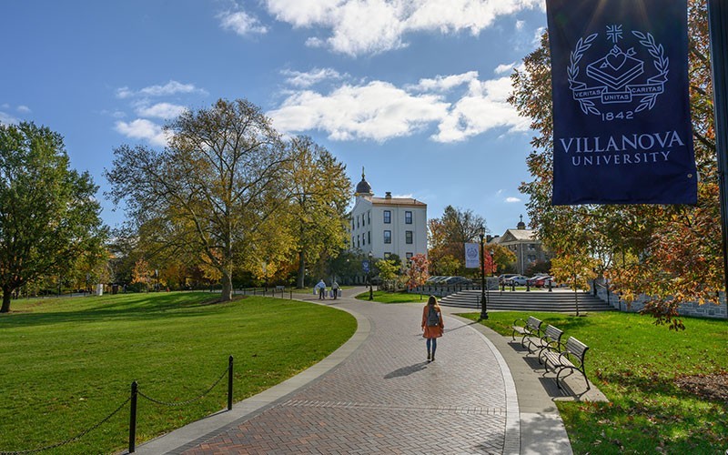 A student walks on the pathway around Mendel Field.