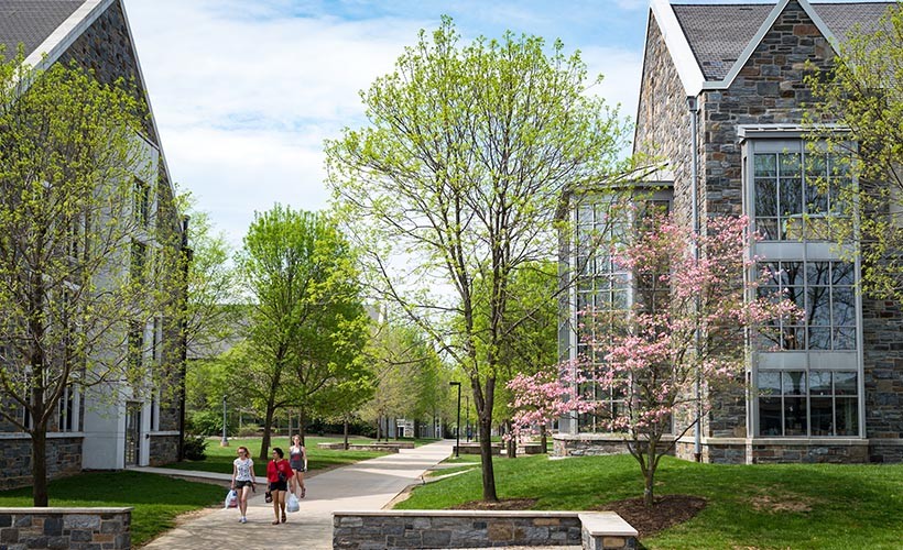 Students walk on a path between two residence halls on west campus.