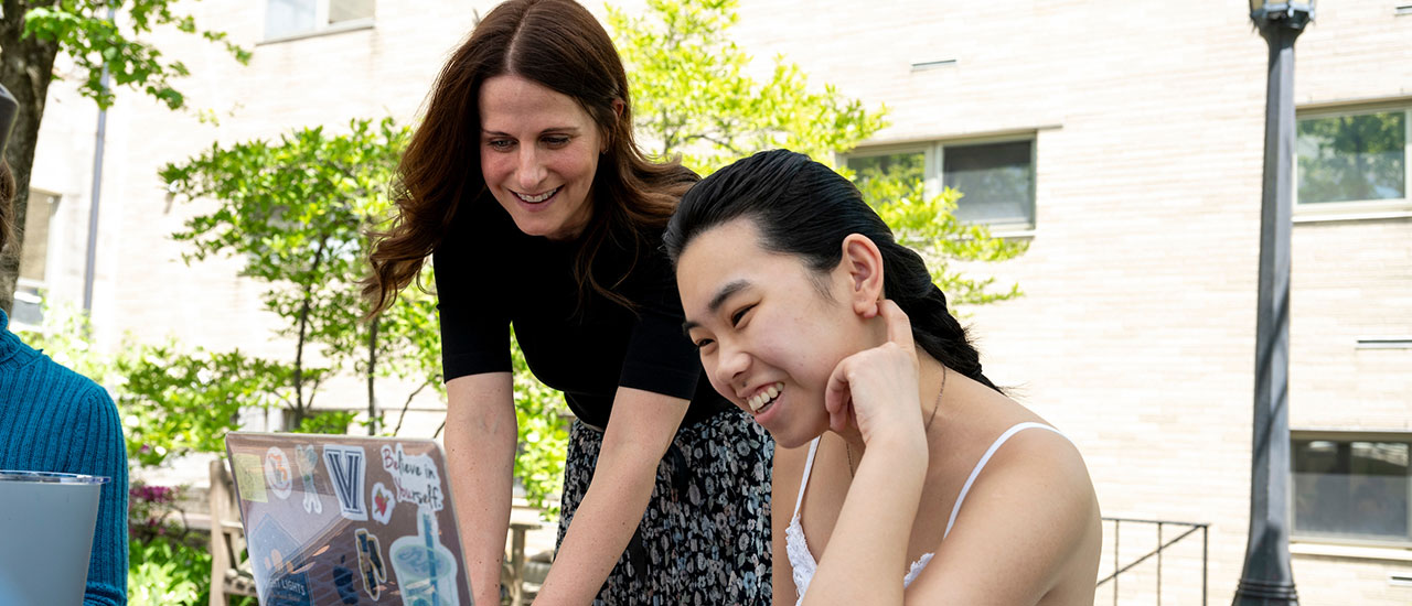 Professor and student looking at a laptop