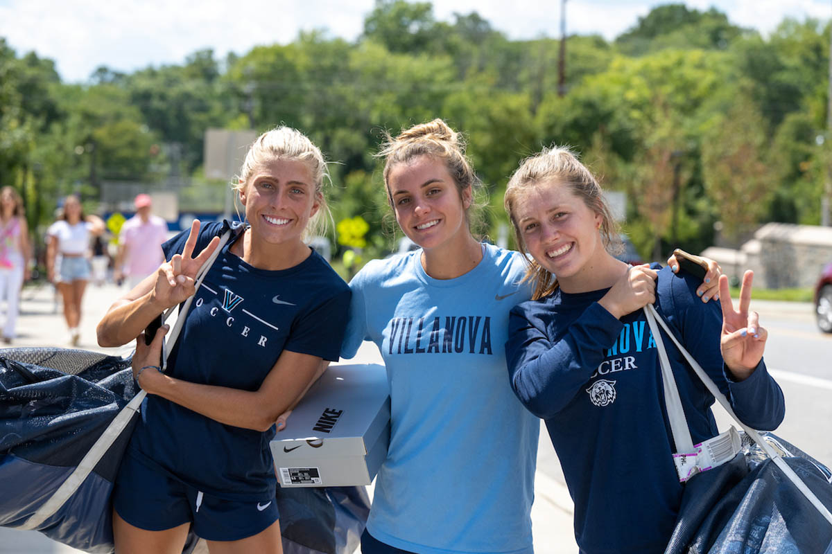 Image of three soccer players throwing up the Villanova "V"