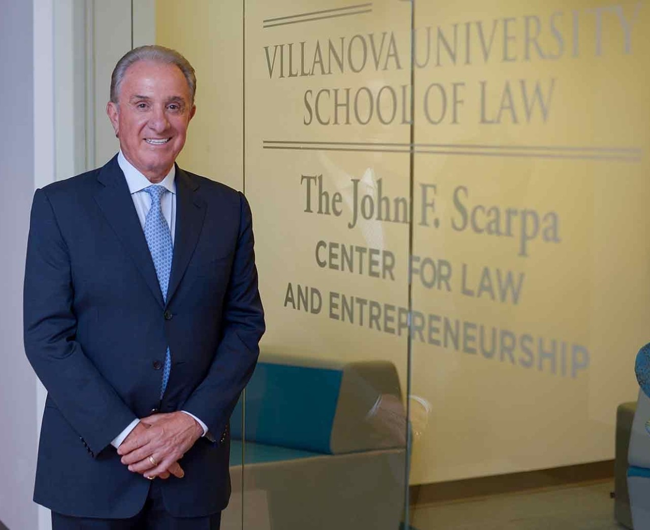 John F. Scarpa in a blue suit and tie standing in front of the  John F. Scarpa Center for Entrepreneurship and Law at Villanova University