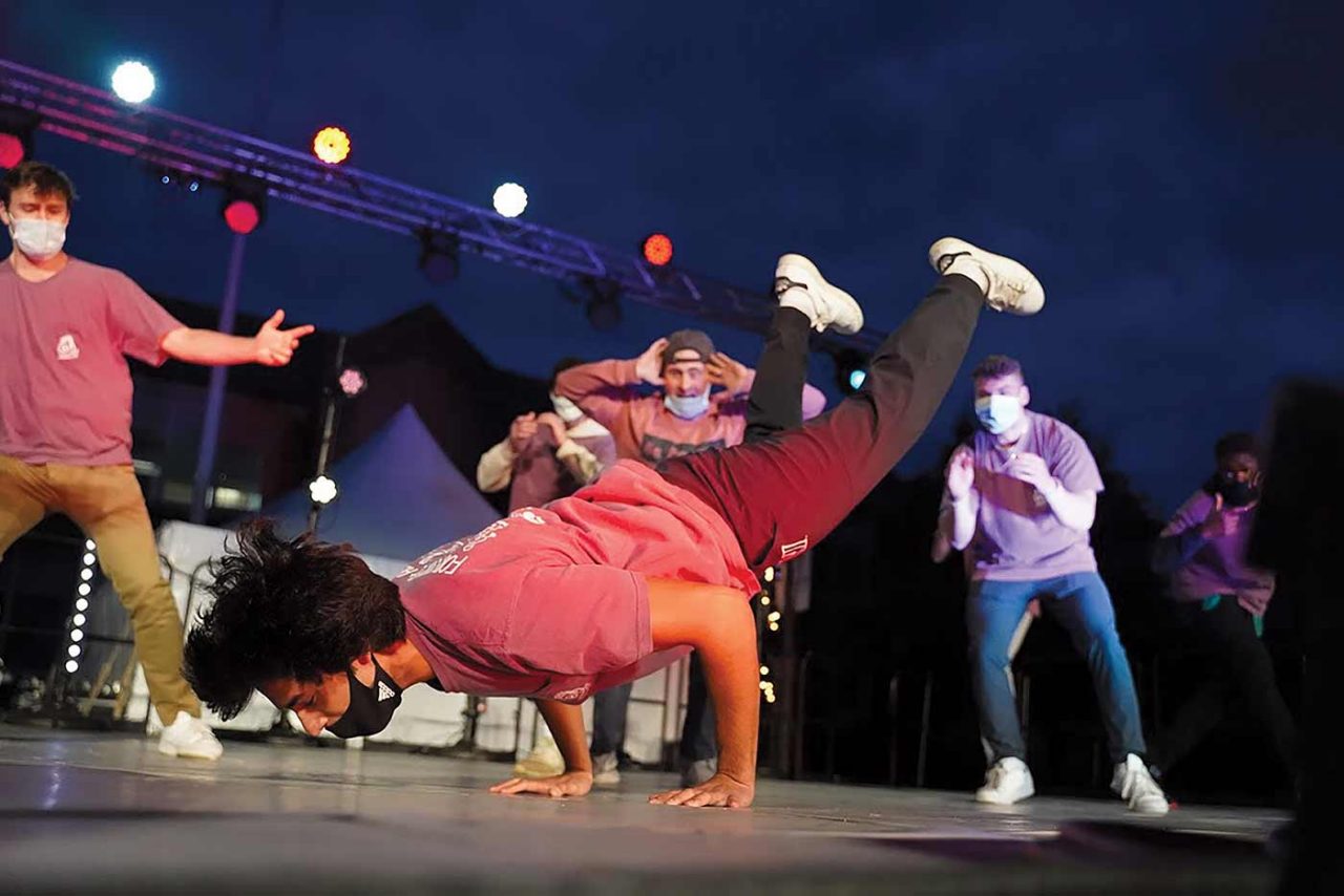 A hip-hop dancer performing on stage surrounded by a group of Villanova students